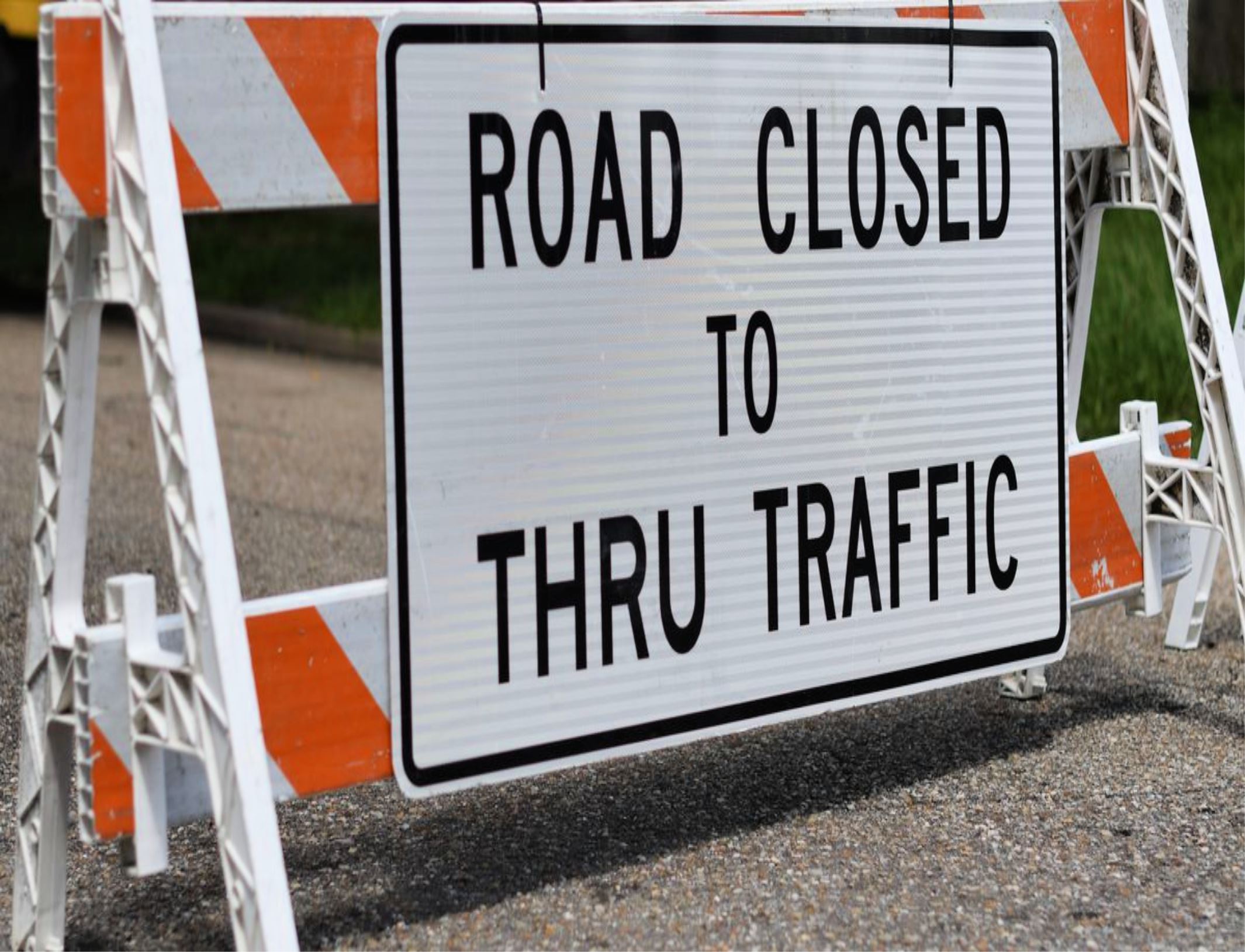 Barrier and sign stating road closed to thru traffic.
